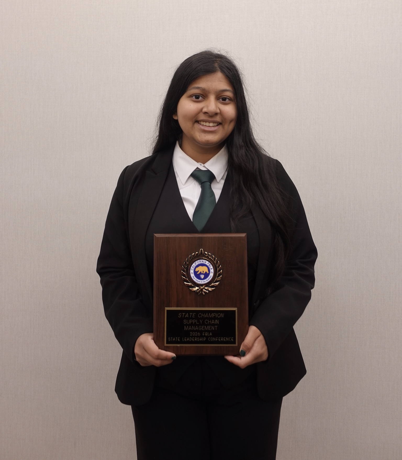 Sufee Kathane holding the FBLA State Champion plaque for Supply Chain Management