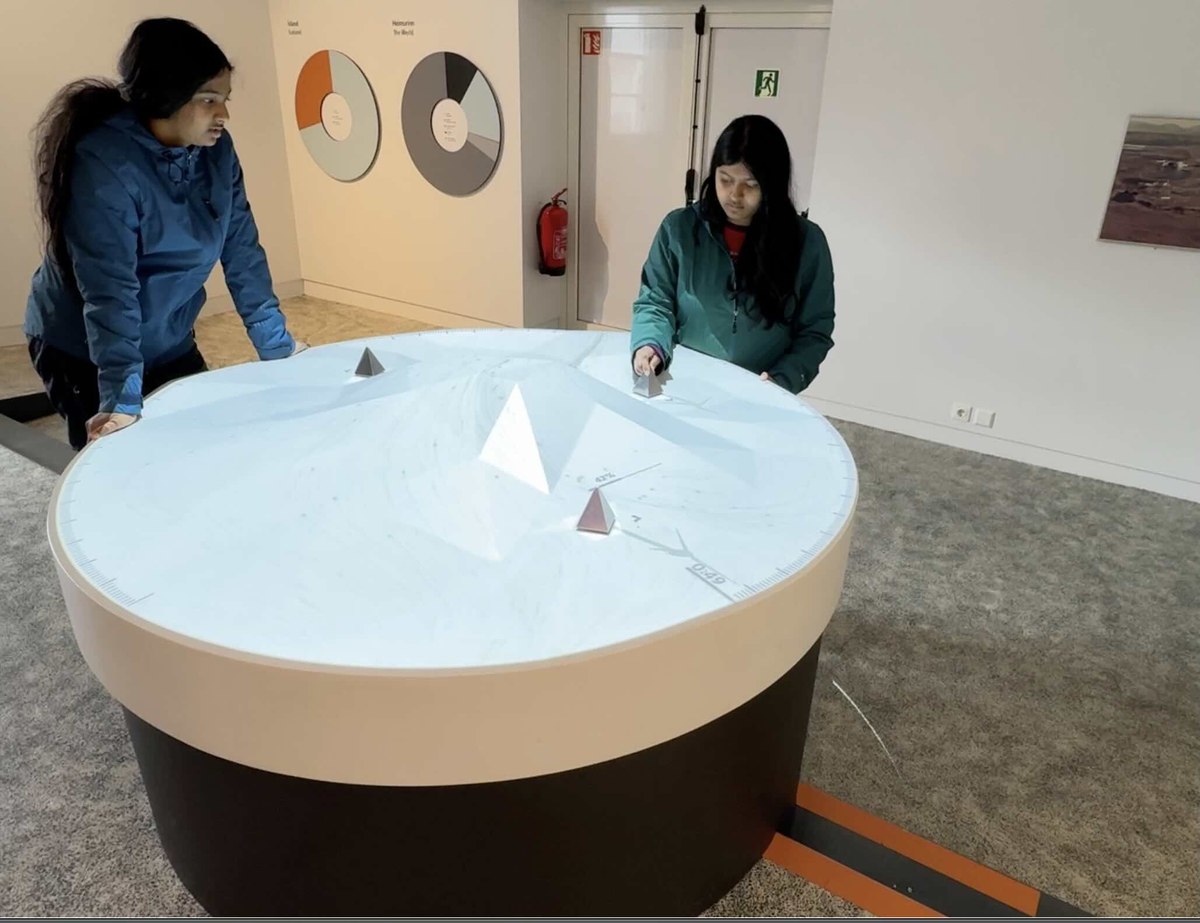 Sufee and her sister exploring an interactive 3D topography table of Iceland